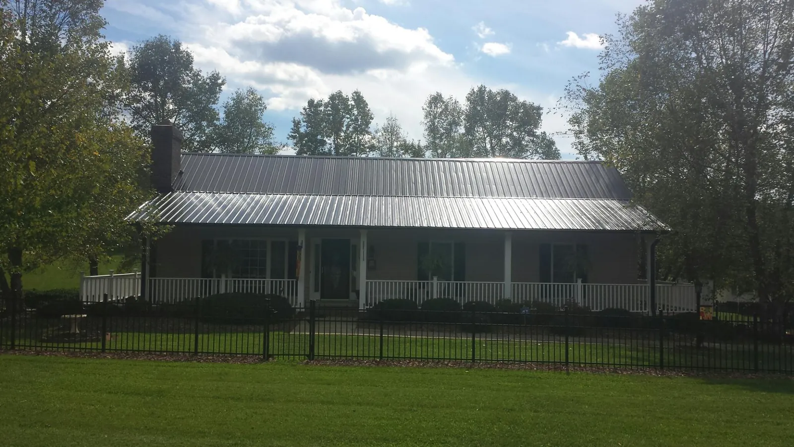 Gray metal roof on a brick ranch with a full width front porch — Gutter Guard Installation work by our crew in Tipton